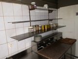 a kitchen with a stove, shelves, and dishes on the counter
