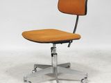 une chaise de bureau orange posée sur un sol blanc