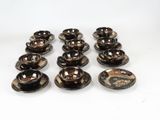 six brown and black bowls and saucers sitting on a white surface