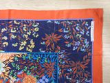 an orange and blue scarf with a picture of flowers and leaves on it