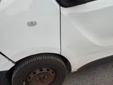 a small white car that has been damaged by the side of the road