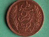 a copper coin with arabic writing on it on a green surface