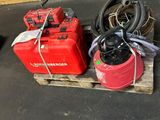 deux bonbonnes de gaz rouges posées sur une palette, auxquelles est raccordé un tuyau