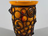 a yellow vase with oranges in it sitting on a table