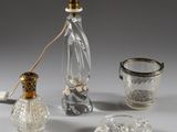 une bouteille en verre, un verre et un bougeoir en verre posés sur une table