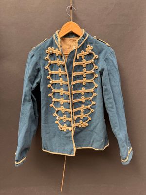 une vieille veste bleue accrochée au mur à côté d'un cintre en bois