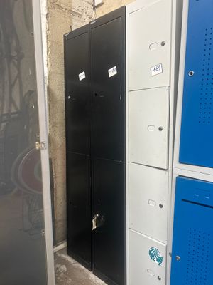 Plusieurs casiers métalliques sont alignés le long d'un mur dans une pièce.