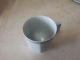 a white cup sitting on a table with a spoon in it