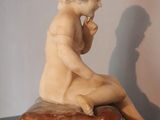 marble statue of a boy sitting on a rock with his hand on his chin