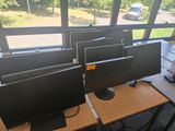de nombreux écrans d'ordinateur posés sur les bureaux de la pièce