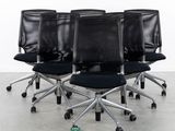 four black office chairs sitting in a row in a white room