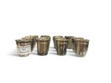six silver shot glasses sitting next to each other on a white surface