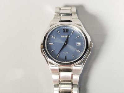 a silver watch with a blue face on a white surface