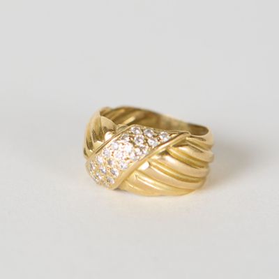 gros plan d'une bague en or avec des diamants sur une surface blanche