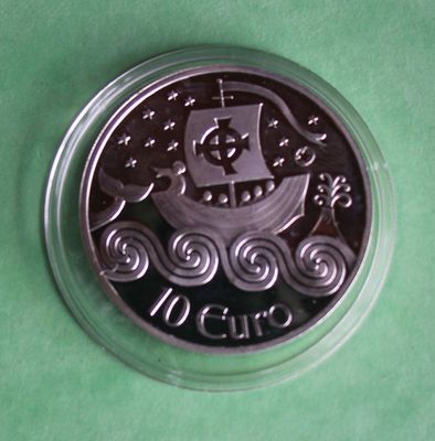 a silver coin with a ship on it on a green surface