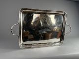 a silver tray with a handle and handles on a table