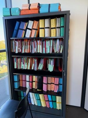 une bibliothèque noire remplie de livres et une chaise devant une fenêtre