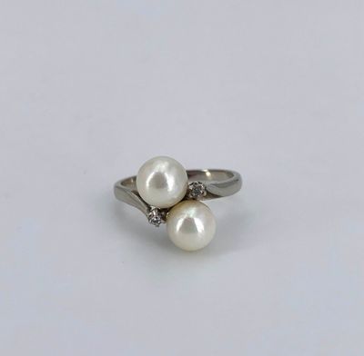 a close up of a white pearl and diamond ring on a white surface