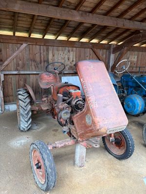 deux vieux tracteurs dans une grange au toit en bois