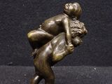 bronze statue of a man wrestling a woman on a black background