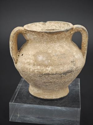 un vase posé sur un socle, sur une surface noire