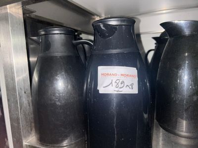 several black vases are lined up on a shelf in a kitchen