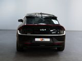 the rear end of a black car in a room with a white wall