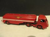 un camion jouet rouge posé sur une surface blanche