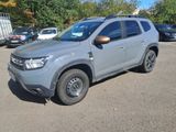 the grey dacia is parked in a parking lot with other cars