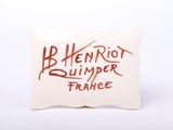 the pillow is white with red writing on it and has a red writing on it
