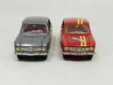 two toy cars sitting next to each other on a white surface