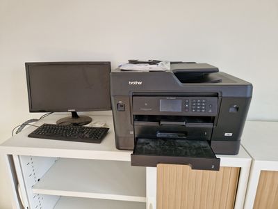 a printer sitting on a desk next to a computer monitor