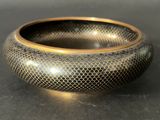a close up of a black and gold bowl on a table