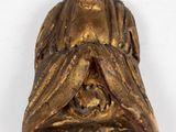 statue of a seated buddha holding a skull on a white surface