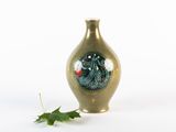 un petit vase orné d'un dessin, à côté d'une feuille