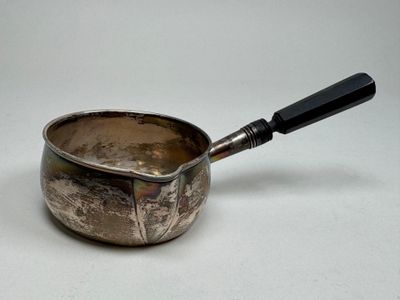 a silver saucepan with a black handle on a white table