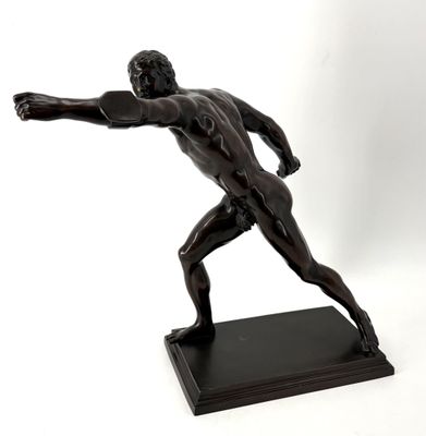 statue en bronze représentant un homme lançant un frisbee sur fond blanc