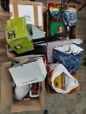 un carton rempli d'objets posé sur un plancher en bois