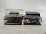 two toy cars are in a display case on a white surface