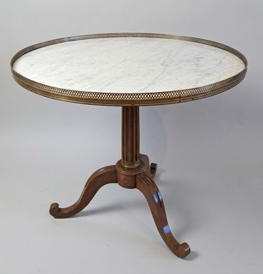 une table au plateau en marbre blanc, avec un piètement en bois, sur fond gris