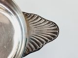 an antique silver plate on a stand on a white surface