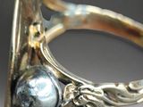 a close up of a silver ring with a pearl on it