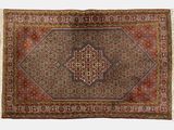 un tapis persan ancien orné d'un motif en médaillon et de franges