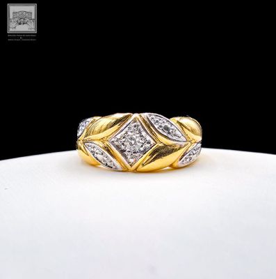a close up of a gold and diamond ring on a white surface