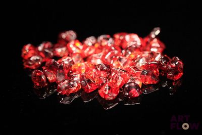 De très jolis cristaux rouges sont disposés sur une surface noire.