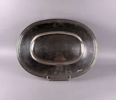 une assiette en argent munie d'une poignée, posée sur un fond blanc