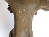 a bronze statue of a tree with a bird on top of it