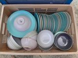 de nombreuses assiettes et bols dans un panier posé par terre