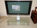 a flat screen tv sitting on a glass table in a living room