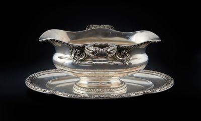 un service en argent ancien composé d'un bol et d'une soucoupe, sur fond noir